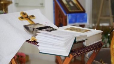 İncil ve Ortodoks haçı kilisede rahibin önünde duruyor. Orta çekim