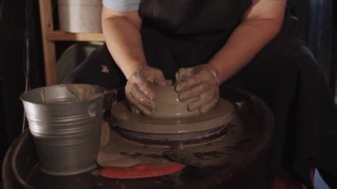 Yaşlı bir kadının elleri atölyede kil tenceresi yapıyor. Orta çekim