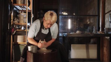 Yaşlı bir çömlekçi kadın geceleri bir atölyede kille çalışıyor. Orta çekim