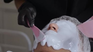 Güzellik salonundaki adamın yüzüne sıvı maske takmak. Orta çekim