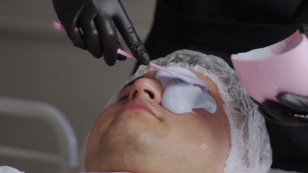 Flüssigmaske Auf Das Gesicht Eines Lächelnden Mannes Schönheitssalon Auftragen Mittelschuss — Stockvideo