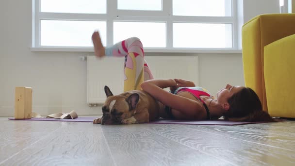 一个女人在她的宠物狗旁边的地板上做伸展运动 — 图库视频影像