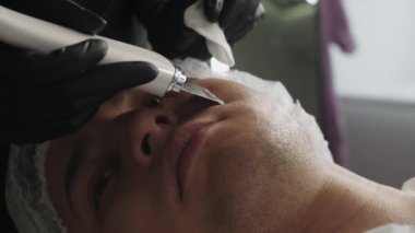 Güzellik tedavileri. Ultrasonik temizleyici kullanan bir adamın yüzünü temizlemek. Orta çekim