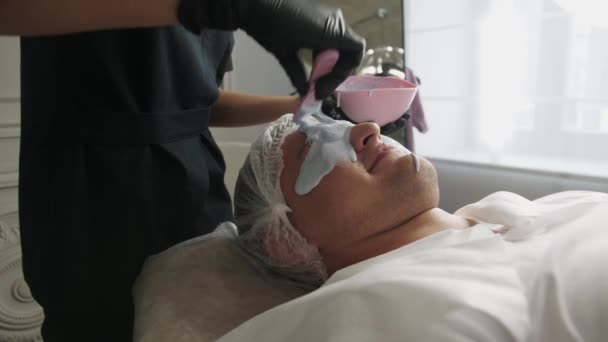 Zabiegi Kosmetologiczne Kosmetolog Kobieta Nakłada Płynną Maskę Twarz Męskiego Klienta — Wideo stockowe