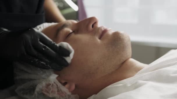 Косметические Процедуры Косметолог Вытирает Лицо Клиента Мужчины Хлопчатобумажными Прокладками Средний — стоковое видео