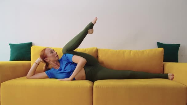 Dorosła Kobieta Leżąca Żółtej Kanapie Rozciągająca Nogę Środek Strzału — Wideo stockowe