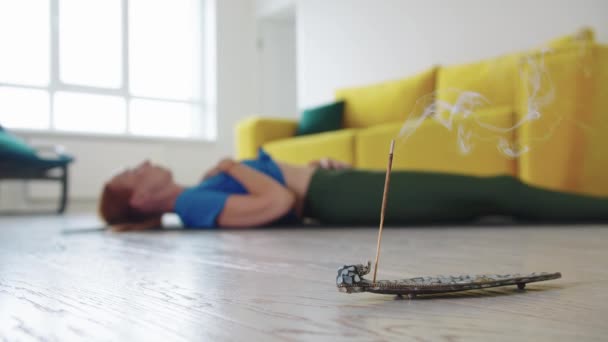 成年妇女躺在地板上 做呼吸练习 在前景上烧香 — 图库视频影像