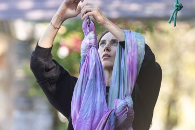 Bir kadın kancaya yoga hamağı asıyor. Orta çekim