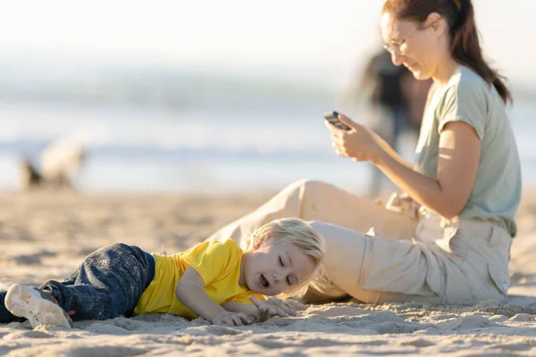 金发碧眼的小男孩和他的母亲在海滩上消磨时光 — 图库照片