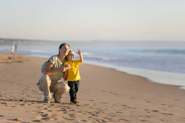 一个金发碧眼的小男孩和他的母亲在海边散步 望着天空 — 图库照片