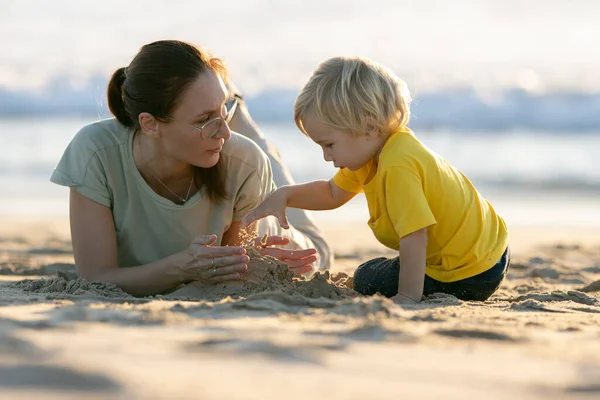 金发碧眼的小男孩和他的母亲在沙滩上玩耍 — 图库照片
