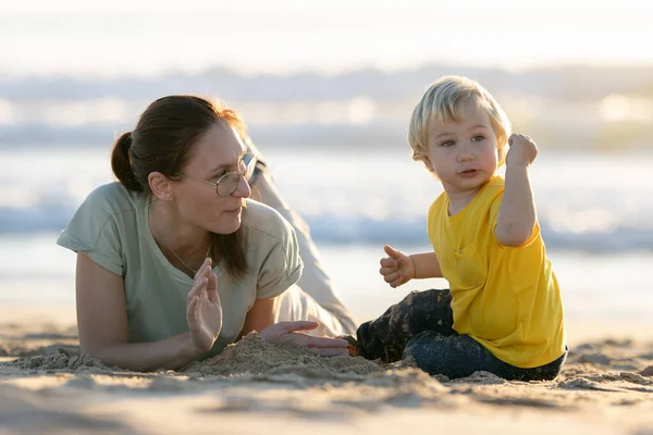 金发碧眼的小男孩和他的妈妈在海滩上玩耍 — 图库照片
