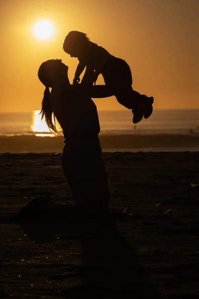 微笑的姜汁女人在橙色的日落海滩抚养着她的小儿子 — 图库照片