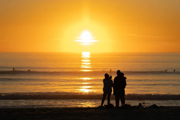 Leuchtend Orangefarbener Sonnenuntergang Über Dem Ozean Silhouetten Von Menschen Die — Stockfoto