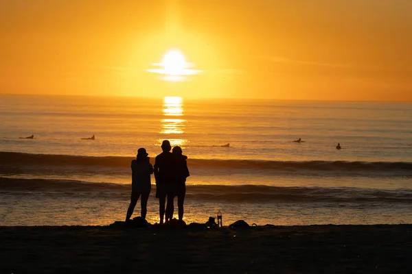 Leuchtend Orangefarbener Sonnenuntergang Über Dem Ozean Schwarze Silhouetten Von Menschen — Stockfoto