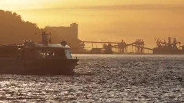 Turist teknesi turuncu bir günbatımında nehirden geçiyor. Orta çekim
