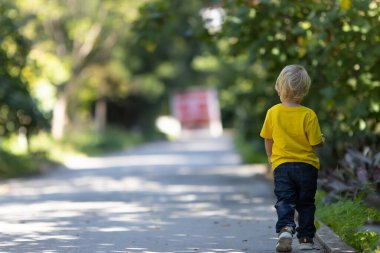 Küçük sarışın çocuk parkta yolda yürüyordu. Orta çekim