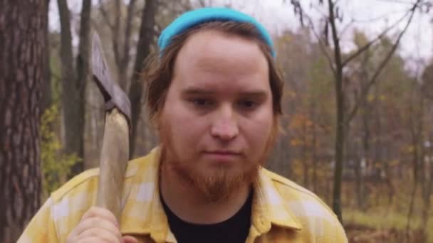 髭を生やした男が秋の森の中を肩に斧で歩く 肖像画 — ストック動画