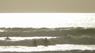 People swimming and surfing in the ocean. Mid shot