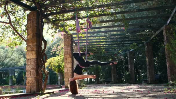 空中ヨガ 庭でハングハンモックを使用して運動する女性 彼女の頭を逆さまにぶら下げています ミッドショット — ストック動画