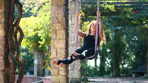 Leende Kvinna Sportdräkt Svingande Yogahängmattan Offentlig Trädgård Mittskott — Stockvideo