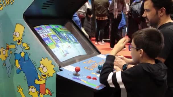 2022 Lisbon Portugal 一个在游戏展台玩 辛普森一家 街机游戏的男孩 — 图库视频影像