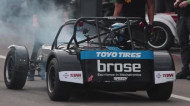 11-20-2022 PORTUGAL, LISBON: Caterham festival of car racing - racer exits a smoking kart at a pit stop - TOYO TIRES advertisement. Mid shot