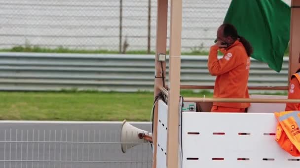 211 2022ポルトガル リスボン カーレースのカターハム祭り 男はレーストラック上のレーサーに緑色の旗を振っています ミッドショット — ストック動画