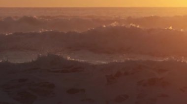 Sea waves raging while orange sunset. Mid shot