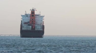 An industrial transport vessel sails on a river. Mid shot