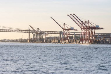 Industrial cranes by the river at early sunset. Mid shot