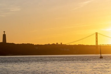 Orange sunset over the Tagus River - the statue of Jesus christ and the bridge over the river. Mid shot
