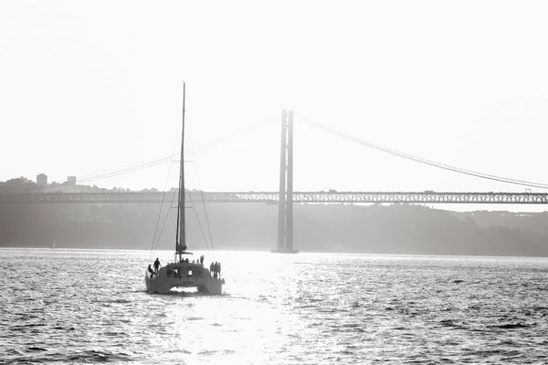 People standing on a sailing yacht sailing along the river towards the bridge. Mid shot