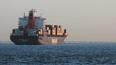 28 November 2022 LISBON, PORTUGAL: HAPAG LLOYD industrial ship sailing in the river and a yacht passing by. Mid shot