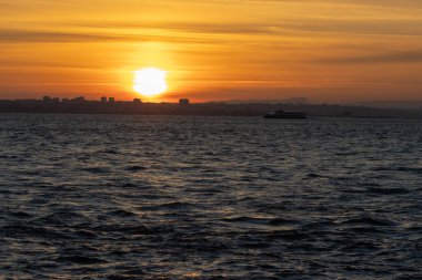 River on an orange bright sunset off Lisbon. Mid shot