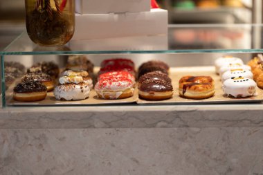 Glass showcase with different delicious glazed donuts. Mid shot