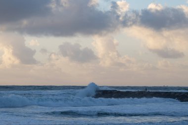 Sea waves crash against a stone ledge. Mid shot