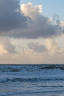 Foamy sea waves at the early evening. Vertical shot