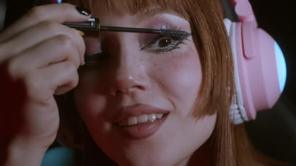 Beautiful Girl Bright Makeup Headphones Puts Mascara Eyelashes Smiles Portrait — Vídeo de Stock