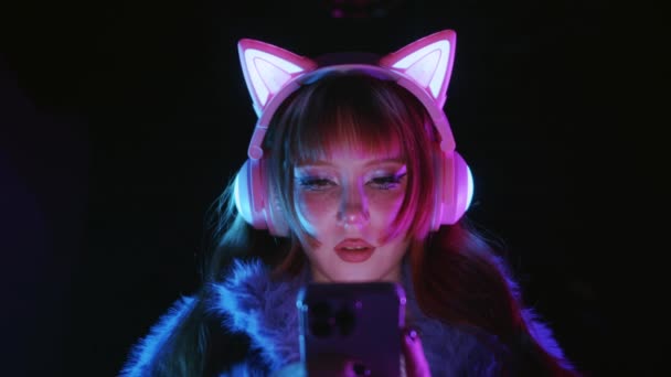 Cute Gamer Girl Using Her Phone Wearing Headphones Luminous Cat — Stock video