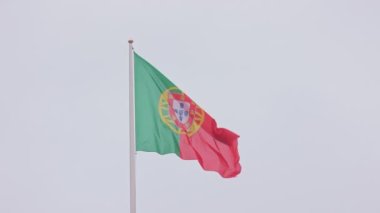 Flag of Portugal on the background of a gray sky. Mid shot