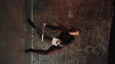 Sexy woman with nice body and long hair dancing on the chair. Vertical shot