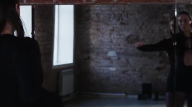 Attractive woman in black body dancing in the studio in front of a mirror. Mid shot