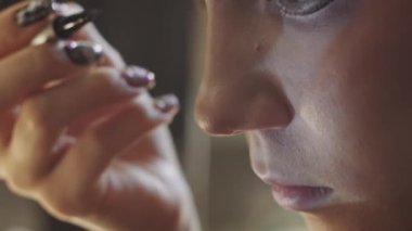 A cute girl doing makeup - drawing dramatic winged eyeliner. Close up