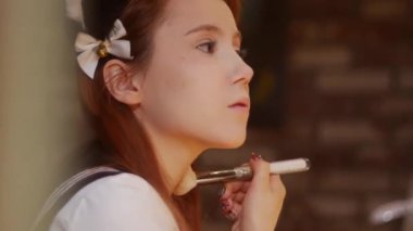 A cute girl cosplayer wearing cat ears doing makeup. Mid shot