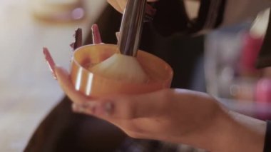 A girl types facial powder on a fluffy brush. Mid shot