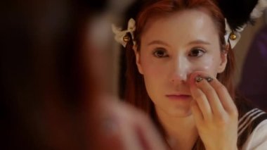A cute girl cosplayer doing makeup - blending concealer using a sponge. Mid shot