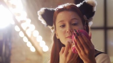 A cute girl cosplayer doing makeup - powdering her face. Portrait