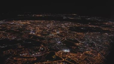 Bright lights of the night city from a birds eye view. Plane passenger POV