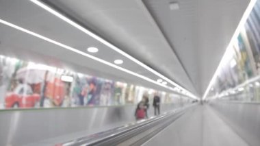 Travolator in the airport - blurred footage - a family rolls an elderly person in a wheelchair on the moving walkway. Mid shot